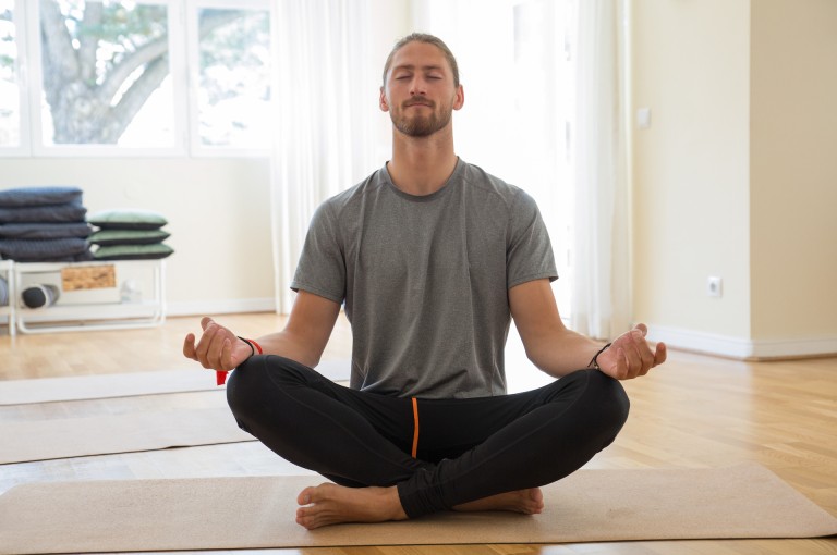Man meditating and holding hands in mudra gesture in class